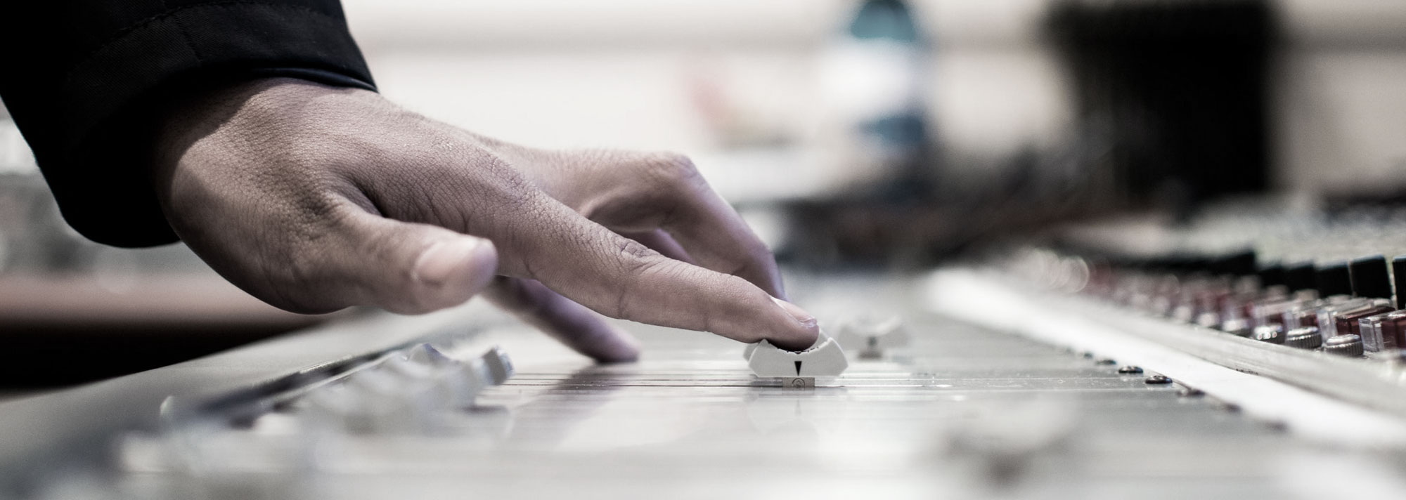 Audio engineer's fingers moving a fader on a large format recording console