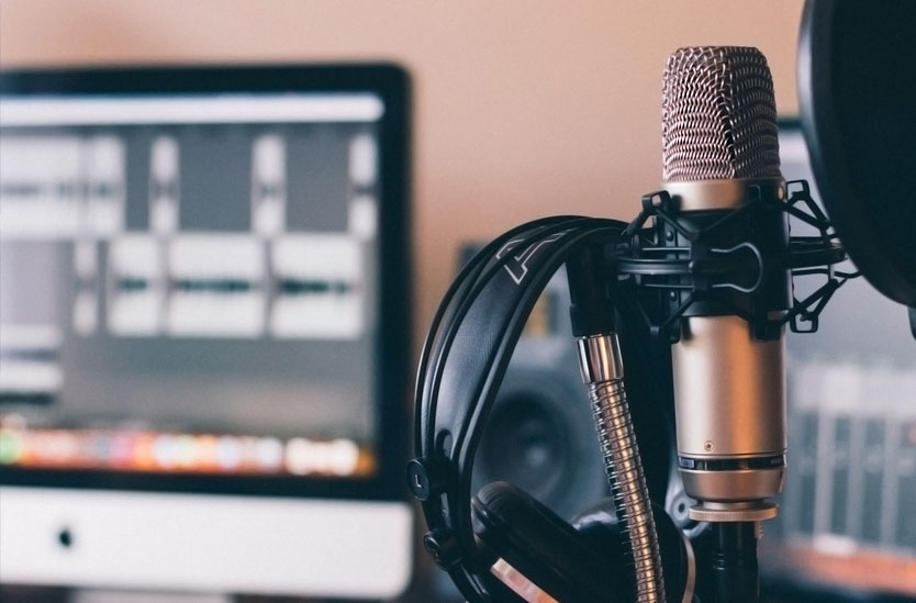 Small recording studio with an iMac, microphone, pop filter, and headphones